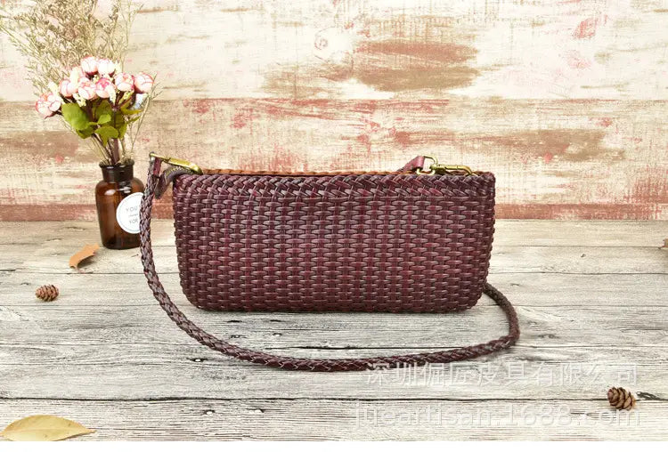 Un sac bandoulière en cuir véritable tressé bordeaux, doté d’une bandoulière tressée et de quincaillerie ton or, conçu comme embrasse en peau de vache en couches.