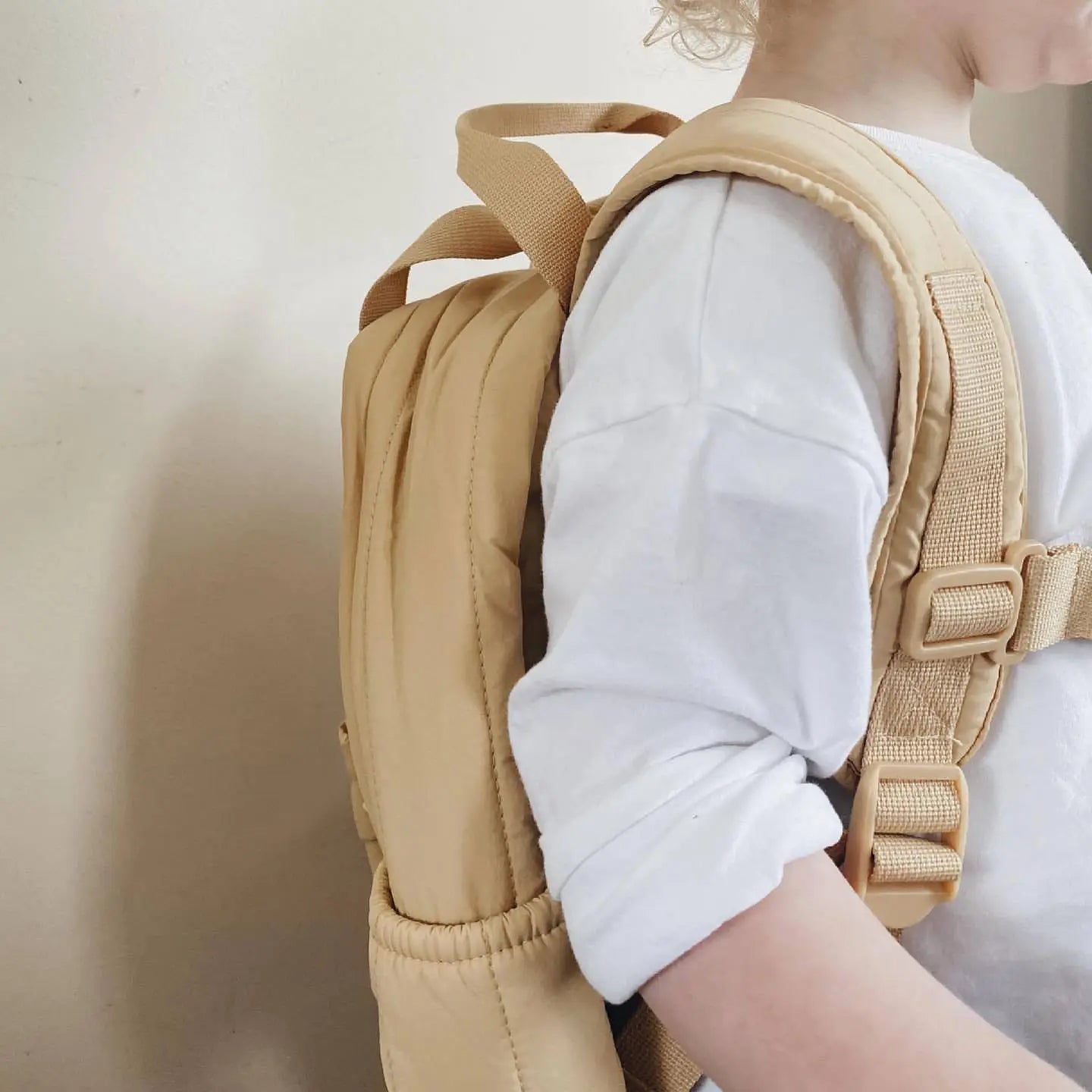 Beiger gesteppt bestickter Rucksack für Kleinkinder mit verstellbaren Schulterträgern und Schnallenverschlüssen, entworfen als wasserfester Schulrucksack für Kinder.