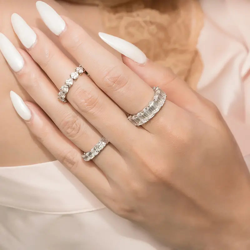 Trois bagues d’éternité cœur en argent sterling, avec des coupes de pierres diamant différentes, ornent les doigts.