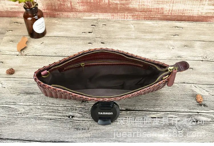 Un sac bandoulière en cuir tressé véritable marron, présentant un design d’embrasse en peau de vache en couches avec fermeture éclair et une doublure intérieure sombre.