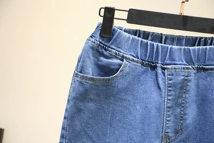 Jeans en denim bleu clair extensible taille haute, avec taille élastique et surpiqûres visibles.