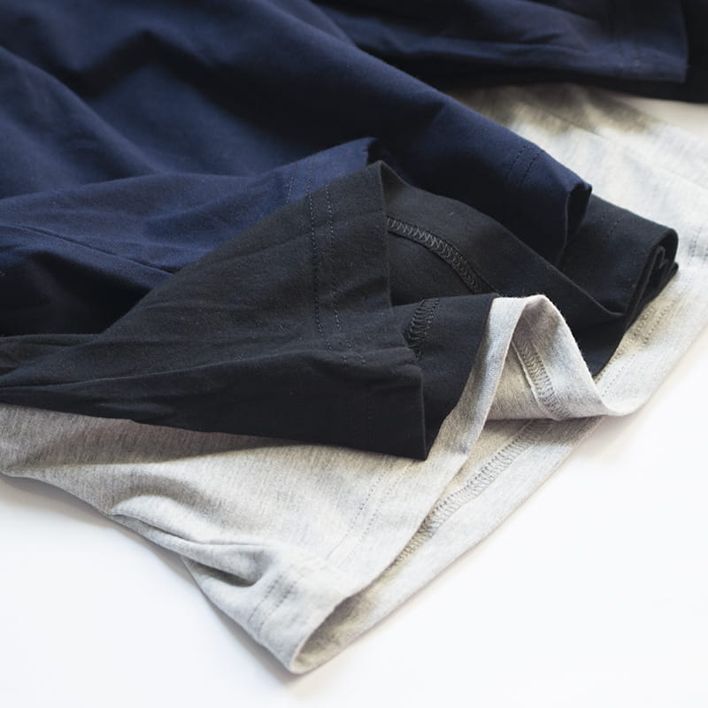 a neatly stacked trio of soft cotton t-shirts in navy blue black and heather gray complementing men cotton boxer shorts loose casual lounge gym jogging white