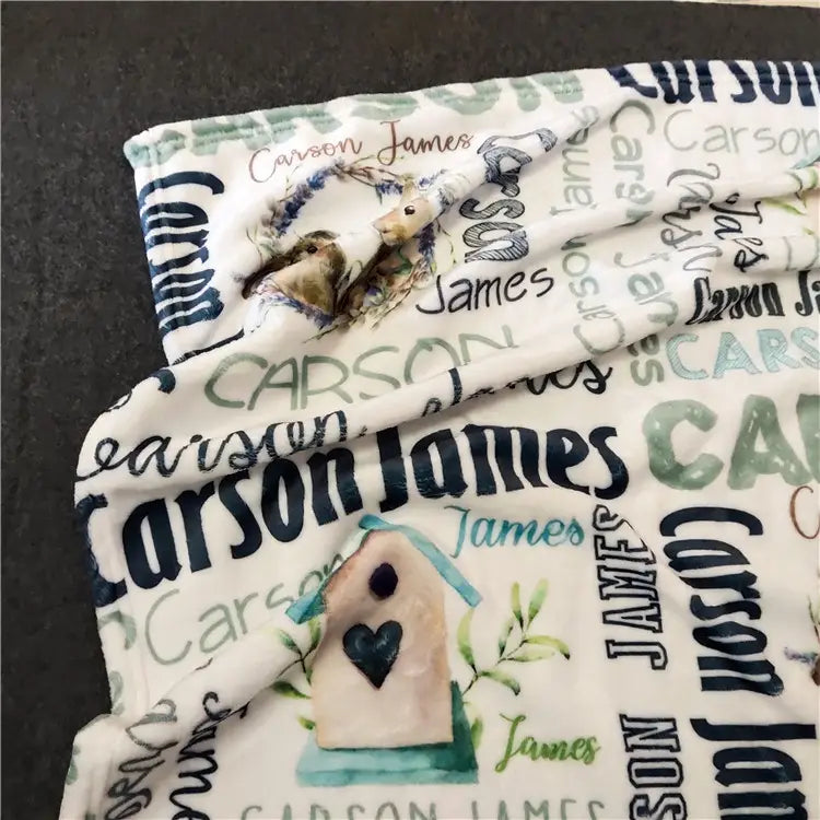 Personalisierte Baby-Wickeldecke aus Fleece für Neugeborene in sanftem Cremefarbton mit einem sich wiederholenden Muster der Namen carson und james in verschiedenen Schriftarten und Farben, begleitet von Vogel- und Vogelhausillustrationen.