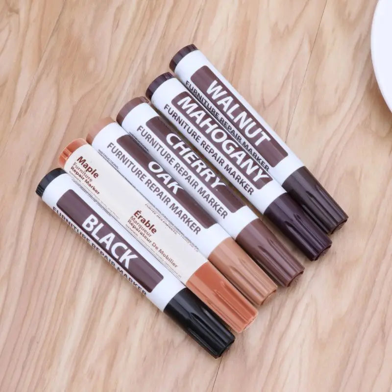 Set of five furniture repair markers with wax sticks in assorted wood tones including black, maple, oak, cherry, mahogany, and walnut for effective furniture repair.