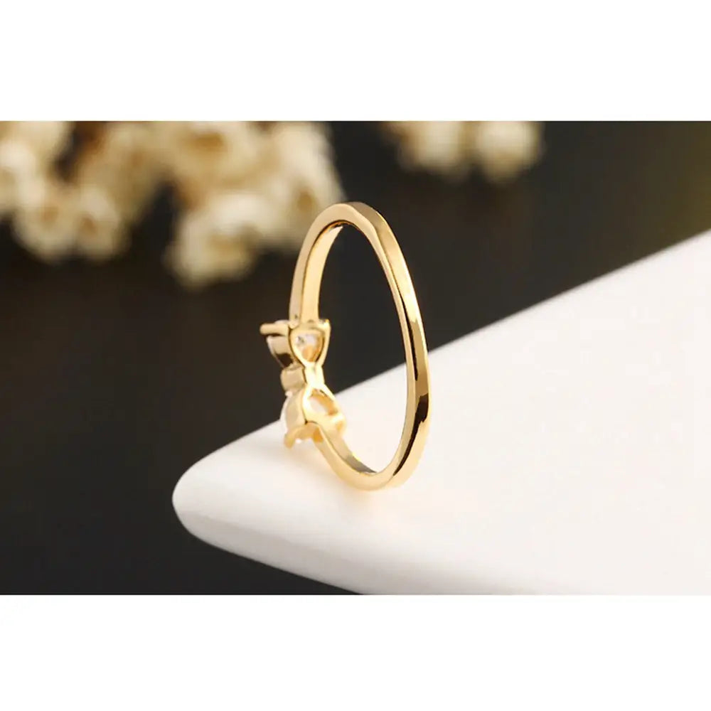 Bague de mariage en argent sterling avec un délicat design de nœud de couleur dorée et une petite pierre en oxyde de zirconium cubique claire placée au centre.