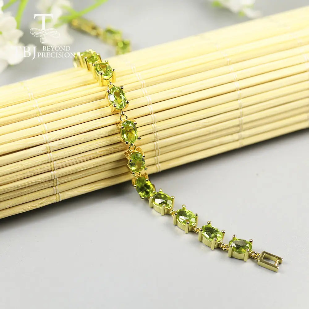 Una pulsera tipo tenis delicada de plata de ley con peridoto, con una fila de vibrantes piedras de peridoto ovaladas verdes, colocadas en elegantes biseles.