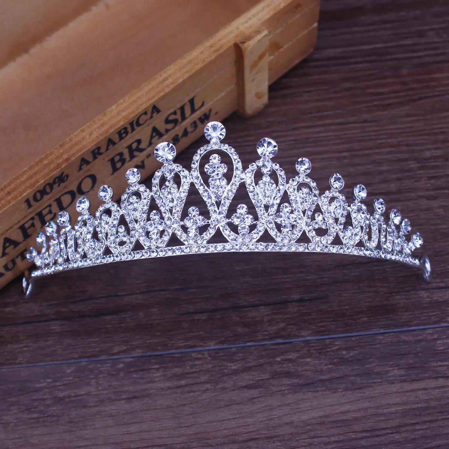 Una tiara de novia de cristal plateado brillante con adornos de cristal florales intrincados y un diseño elaborado para vestir en bodas.