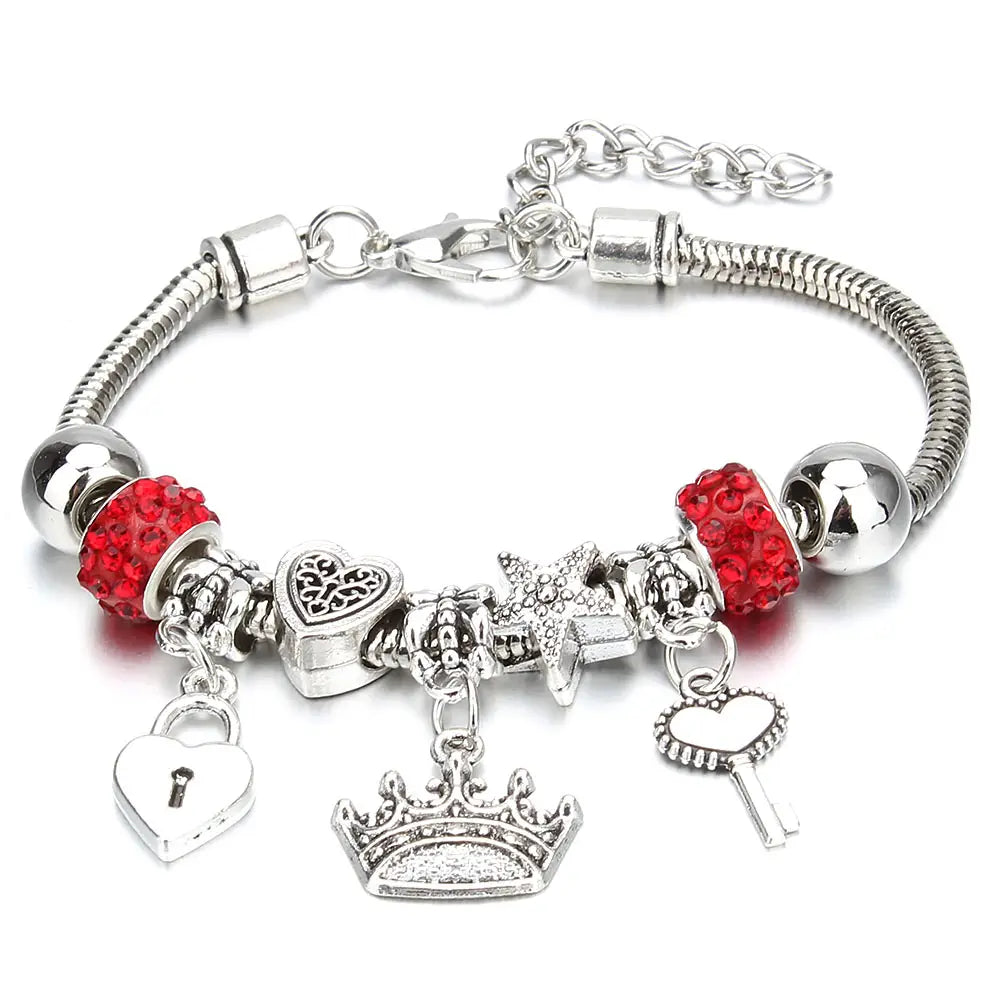 Charm bracelet for women featuring a silver snake chain beaded bracelet adorned with red crystal beads and dangling heart lock crown and key charms.