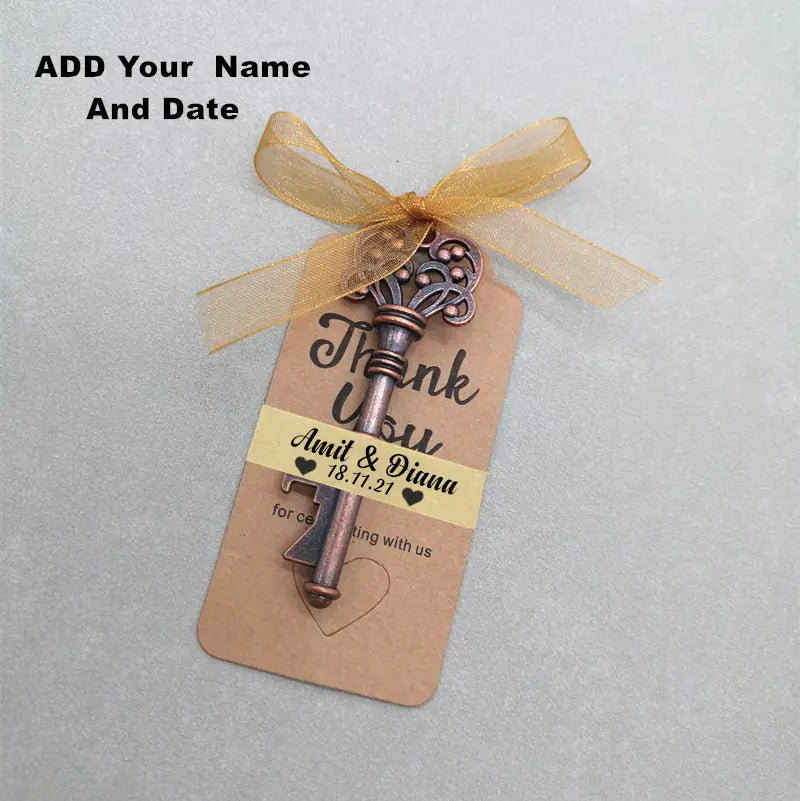 Encanto de llave antigua color bronce con detalles intrincados atado a una etiqueta de papel kraft con cinta dorada y mensaje de boda personalizado para recuerdos abridores de botellas para bodas personalizados.