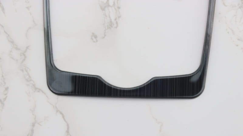 Rahmen für das schwarze Kennzeichen aus Kunststoff mit glänzendem Finish und subtiler horizontaler Struktur entlang der unteren Kante für die Einfassung des Audi A4 B9 A5 Schalthebel-Wandhalters für den Becherhalter.