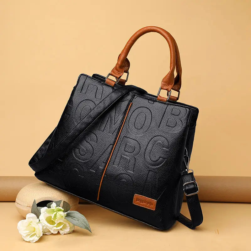 Black crossbody handbag style1 style2 in black textured pu leather with embossed lettering and tan handles satchel style