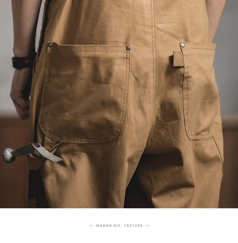 La face arrière des salopettes de travail vintage en toile beige Maden présente un matériau en coton ciré beige, avec des coutures robustes et des rivets métalliques sur les poches arrière.
