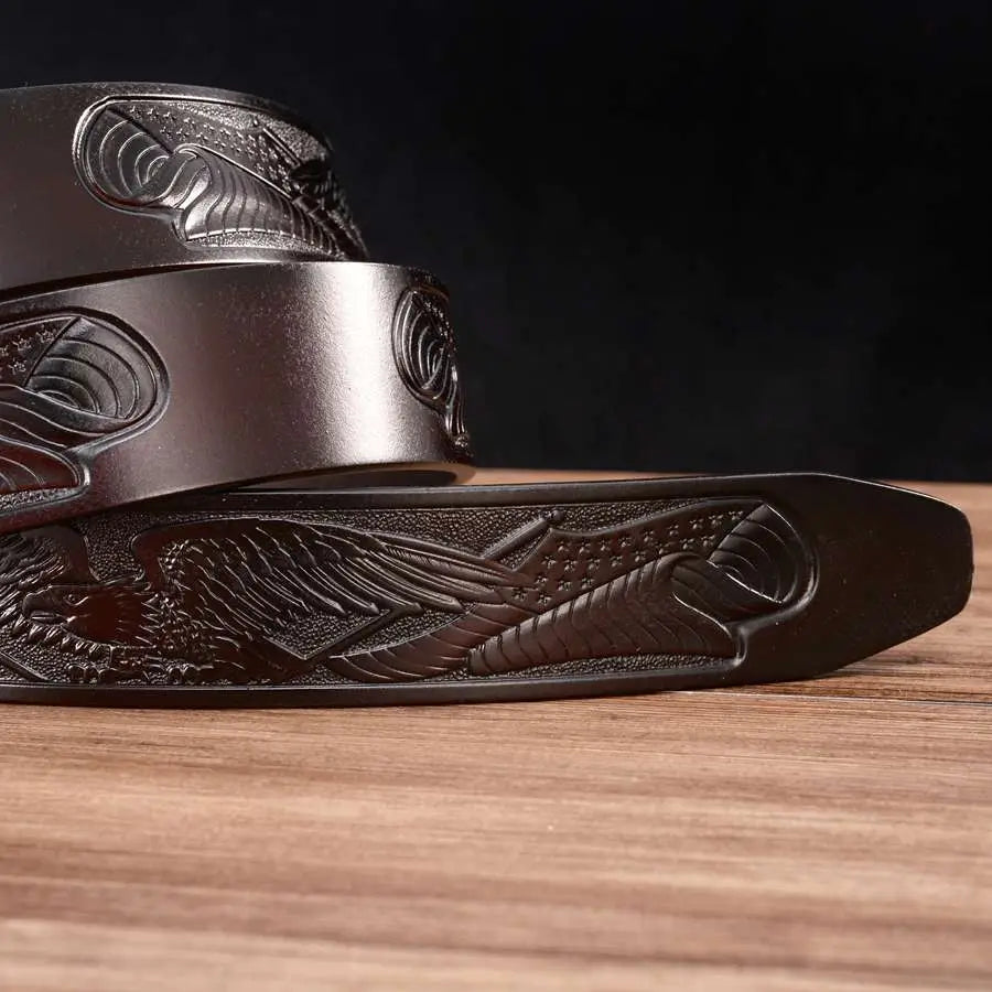 Ceinture à cliquet en cuir brun foncé pour homme, avec un motif d’aigle gaufré, des motifs de plumes détaillés et un léger éclat.
