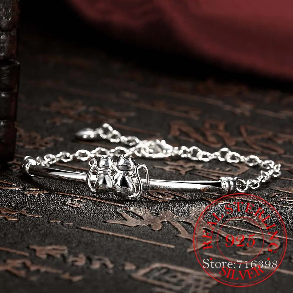 Bracelet en argent sterling avec pendentif couple de chats, présentant deux figures de chat finement conçues sur une chaîne polie et élégante.