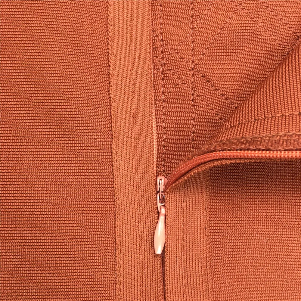 Gros plan sur la tirette de fermeture éclair en maille texturée couleur rouille sur une jupe midi bandeau pour femme à taille haute, style crayon, en orange.