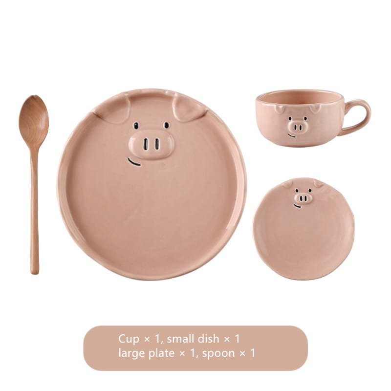 Pastel pink ceramic pig-themed cute pig ceramic dinnerware set featuring a large plate, small dish, cup, and wooden spoon.