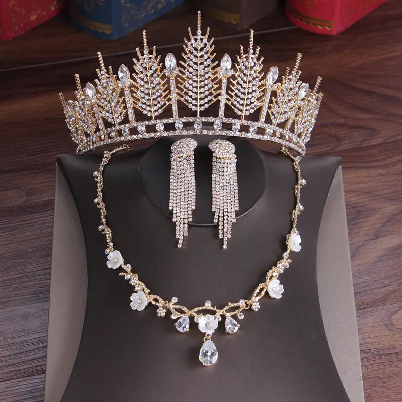 Gold-colored crystal bridal tiara and wedding crown headpiece adorned with intricate leaf and crystal designs featuring sparkling clear rhinestones.