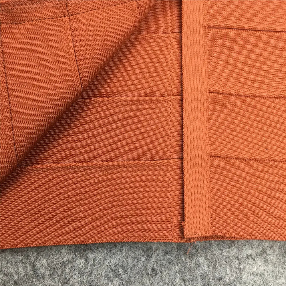Tissu tricoté orange à texture côtelée et coutures visibles le long des assemblages d’une jupe midi bandeau pour femme à taille haute, style crayon.