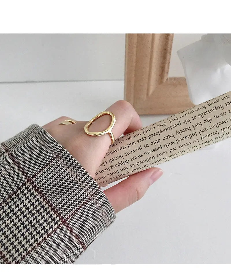 Gold-toned sterling silver adjustable open ring with a sleek minimalist oval design worn on a finger
