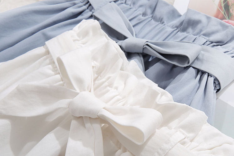 Nœud en satin blanc noué à la taille d’une jupe midi en coton bleu clair, taille haute, robe décontractée en ligne A, présentée du côté arrière.