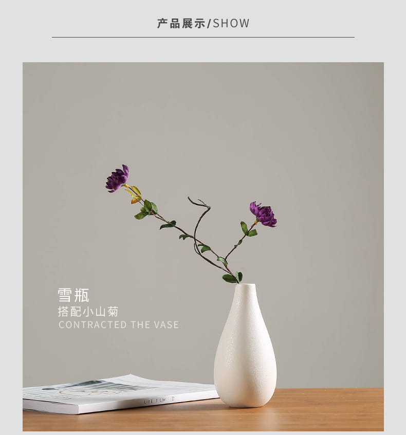A sleek modern white ceramic vase with a smooth tapered design holds two delicate purple flowers for floral decor.
