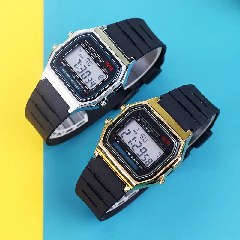 Two digital led sport watches with black rubber straps and metallic cases in silver and gold featuring retro square faces displaying time on a bright blue background.