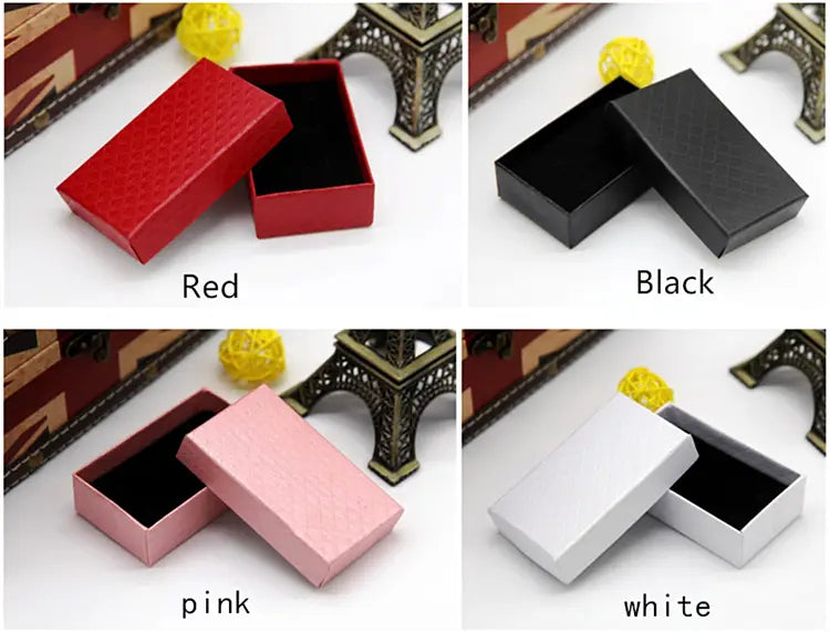 Des boîtes-cadeaux rectangulaires en rouge, noir, rose et blanc, avec des couvercles texturés et des intérieurs noirs, pour des faveurs de mariage personnalisées en décapsuleur en forme de cœur.