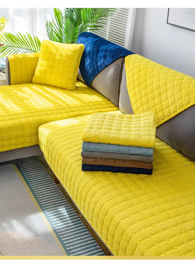 Housse de canapé antidérapante en velours côtelé matelassé jaune vif avec motif cousu en losanges, présentée à côté de housses pliées en gris bleu et brun.