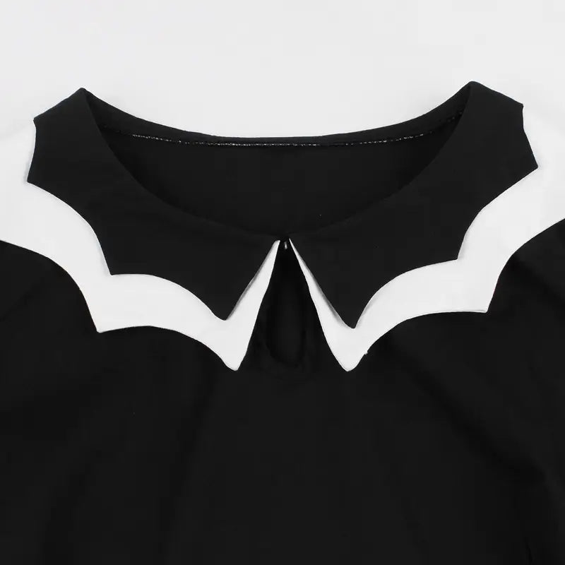 schwarzes Oberteil mit markantem weißem geripptem Peter-Pan-Kragen, dargestellt an der Vorderansicht eines Vintage-Bat-Embroiderie-A-Linien-Kleides
