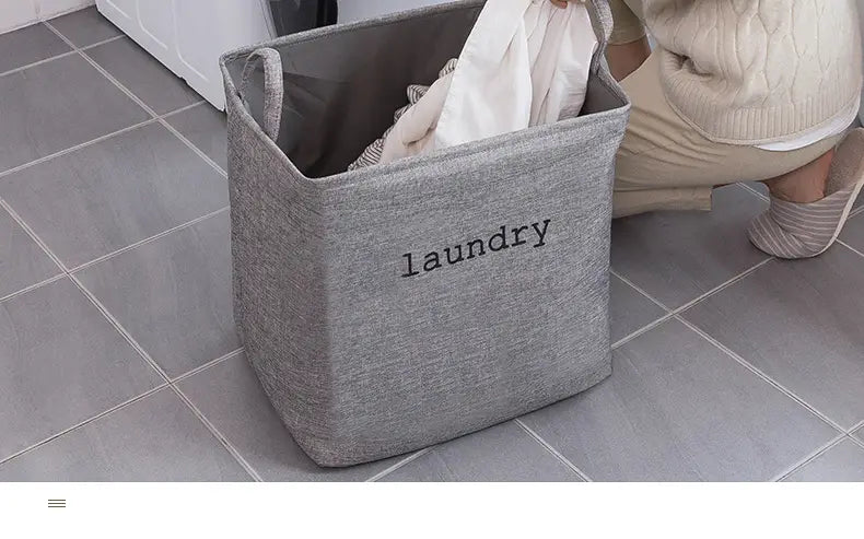 Gray fabric laundry basket with laundry embroidered in black, foldable storage basket ideal for organizing clothes and household items.