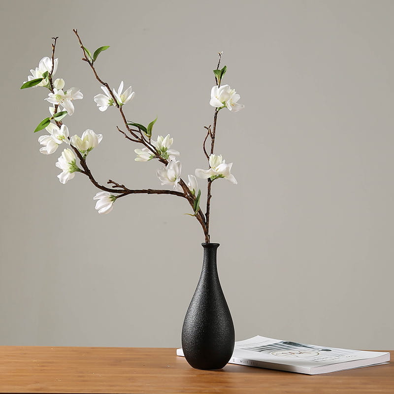 black textured ceramic vase holding white blossoms on dark branches for modern white ceramic floral decor