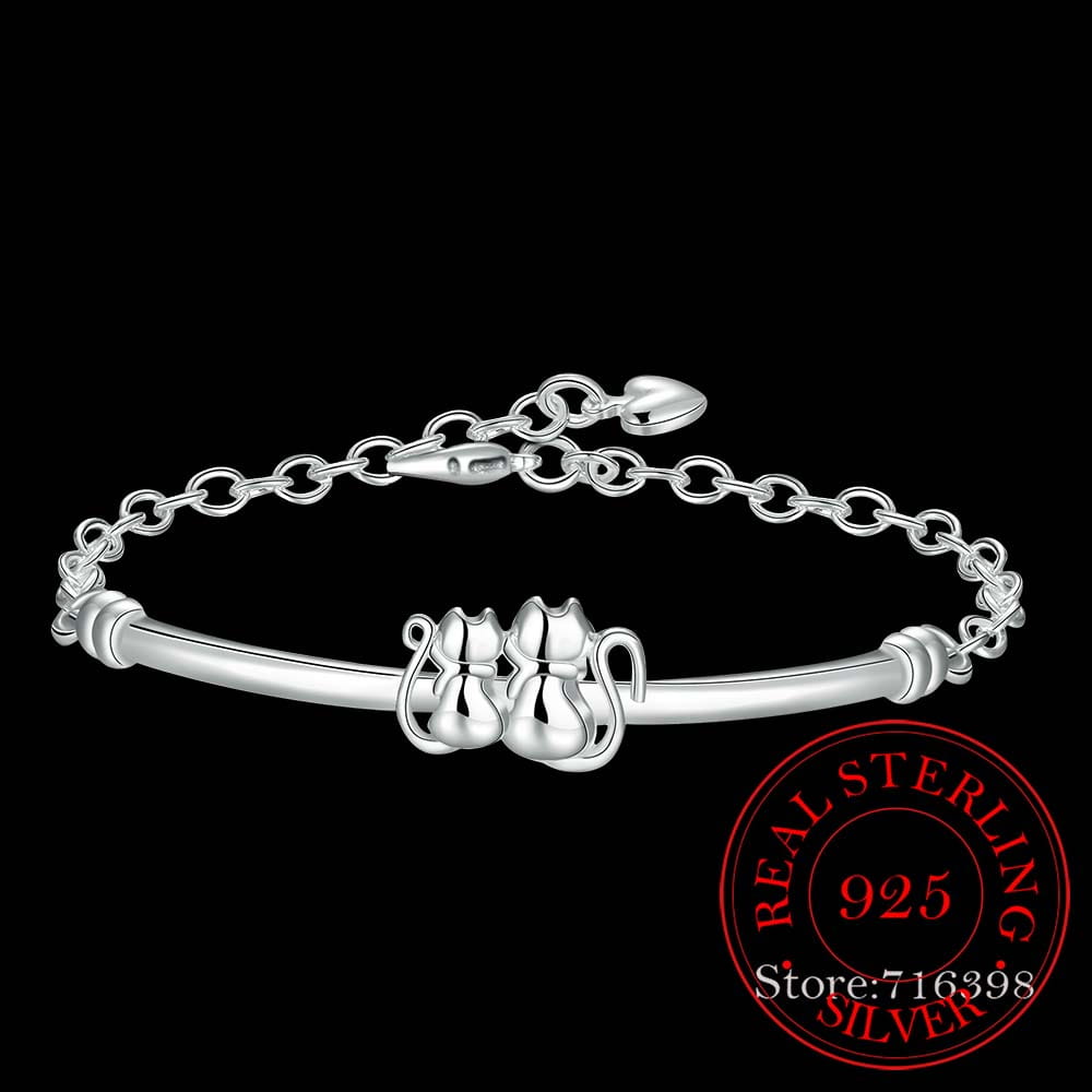 Le bracelet en argent sterling avec pendentif couple de chats présente un bracelet réglable délicat en argent, avec deux figures de chat entrelacées et un fermoir à chaîne.