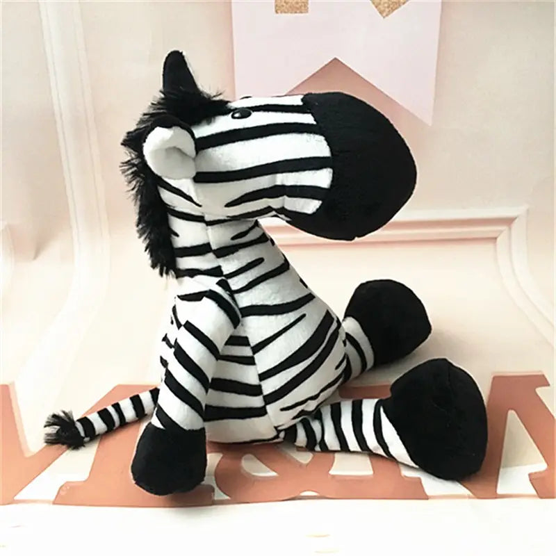 Jouet zèbre rayé noir et blanc en peluche, fabriqué dans un tissu doux, présenté parmi les animaux en peluche rembourrés, notamment lion, éléphant, tigre, de la forêt