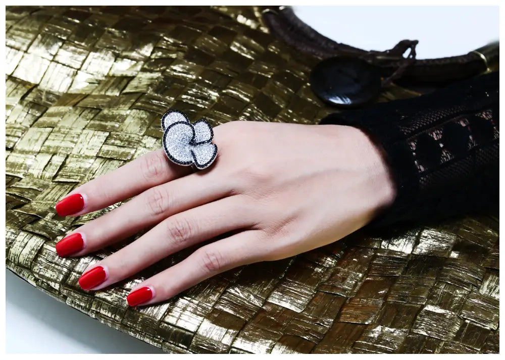 A silver cloud-shaped ring with a textured embroidered finish as a black and white crystal statement flower ring.