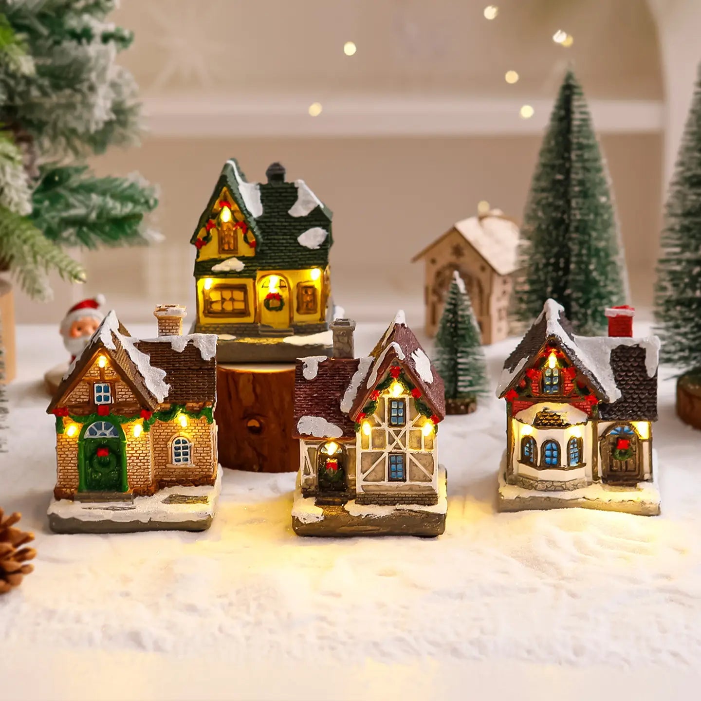 Ornement de maison de village de Noël éclairée présentant des maisons miniatures illuminées, des toits couverts de neige et des lumières festives pour la décoration des fêtes.