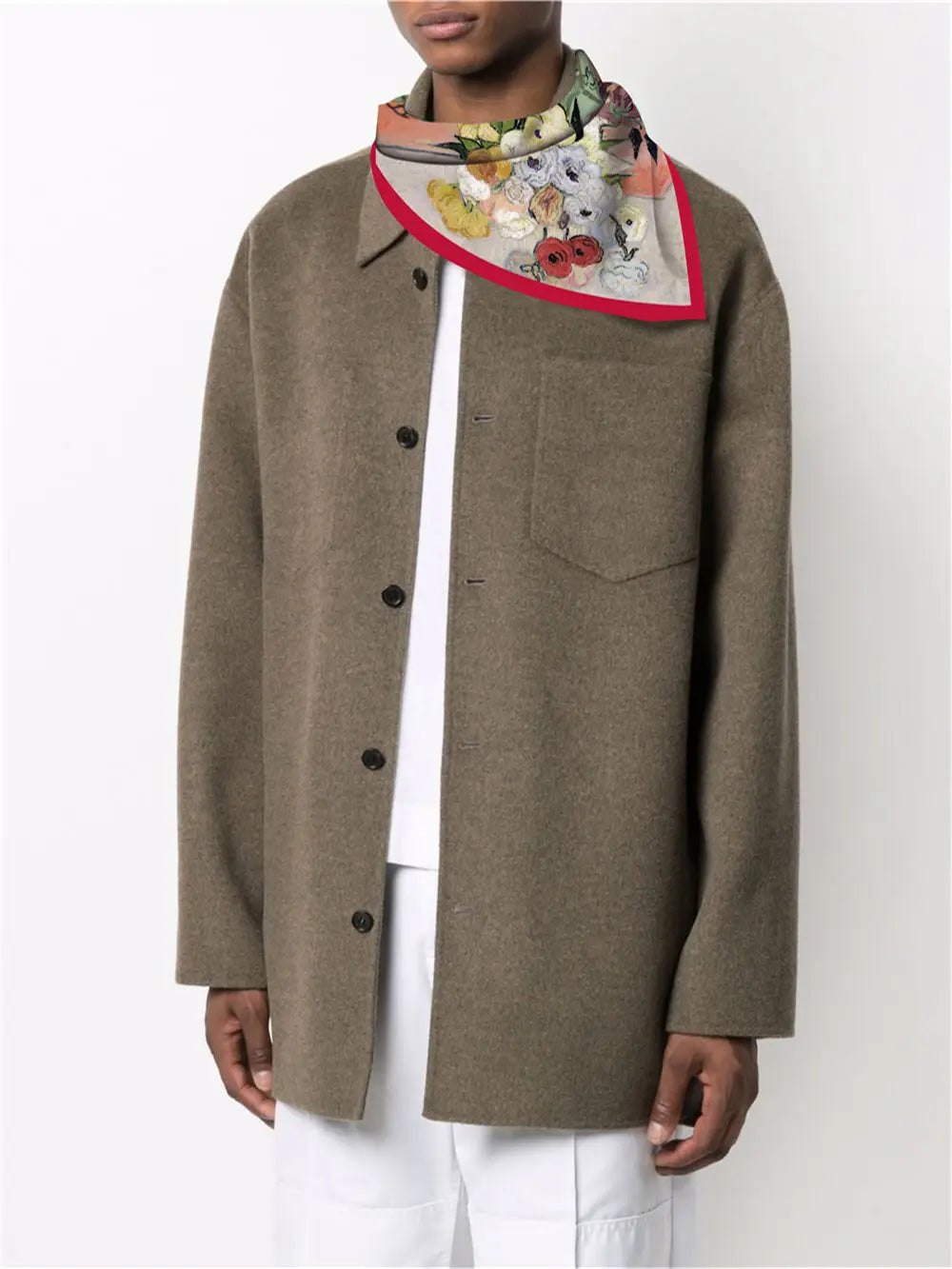 Un foulard carré en soie à motif floral avec une bordure rouge éclatante porté comme accessoire de cou.