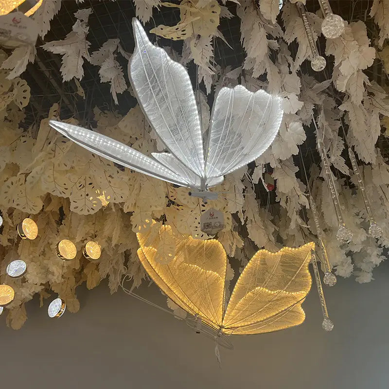 Silber- und goldfarbene, beleuchtete Schmetterlingsförmige Dekorationslichter aus leuchtendem Material, die von der Decke herabhängen, für Hochzeitsdekoration auf der Bühne.