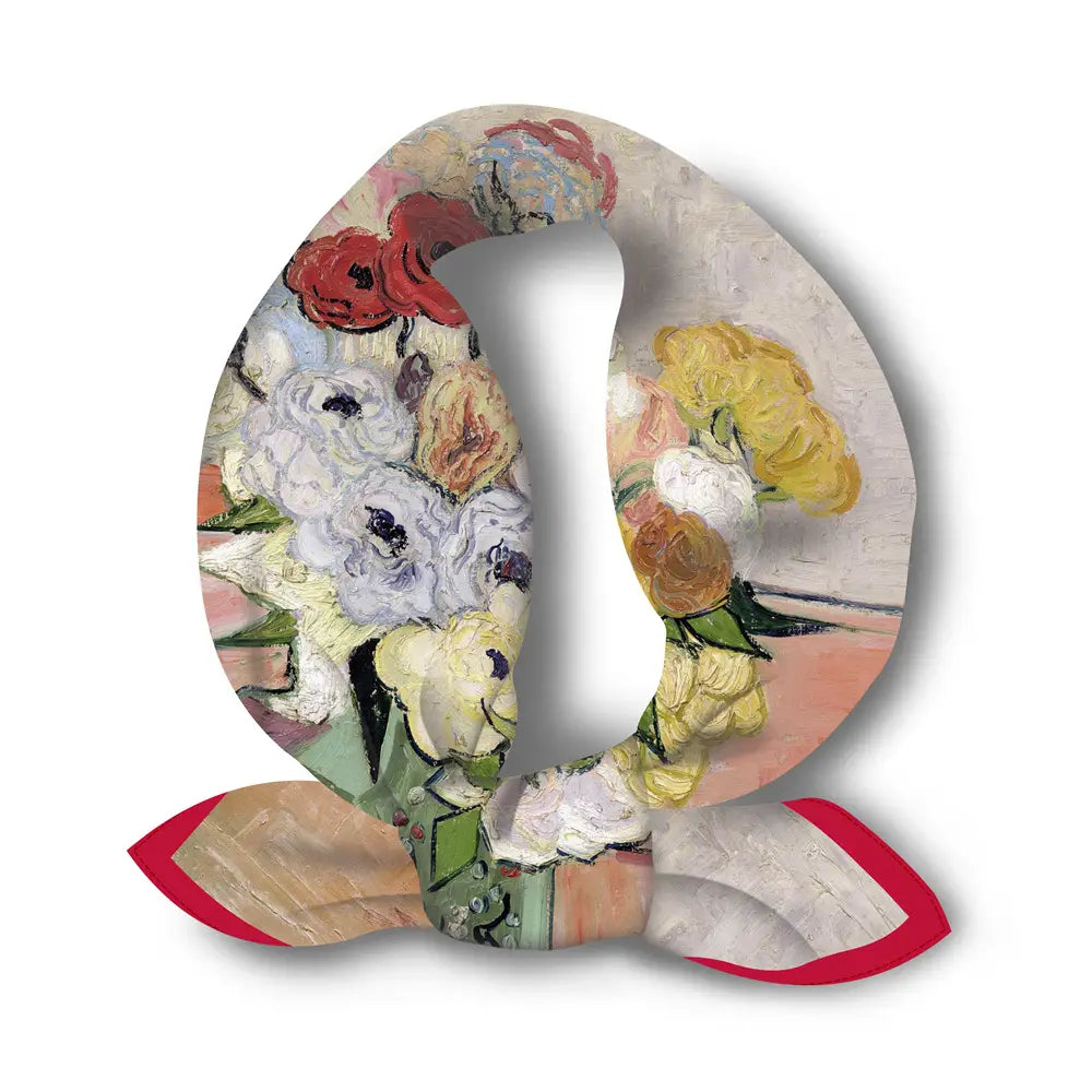 Un foulard carré en soie à motif floral vibrant avec bordure rouge, présentant des teintes rouges, blanches, jaunes et vertes marquées dans un style impressionniste.