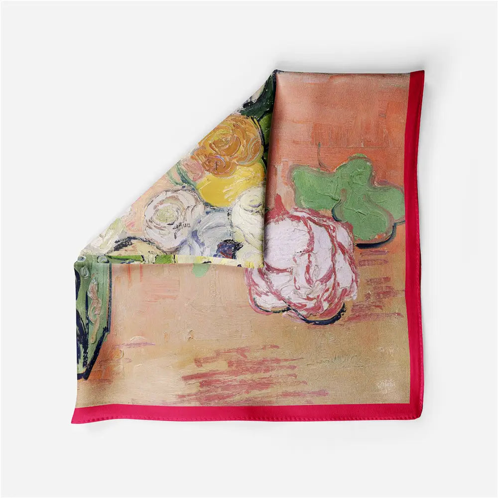 Un foulard carré en soie à motif floral avec un design floral impressionniste vibrant et des bordures rouges marquées, comportant des fleurs peintes en jaune, blanc, vert et rose.