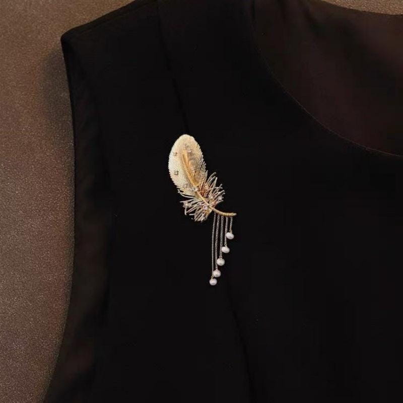 Broche à pompon en perles de plume dorée délicate, ornée de strass étincelants et de perles pendantes.