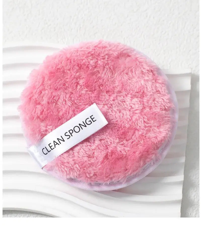 pink fluffy circular makeup sponge with a white clean sponge label from a makeup brush and sponge set 46 piece pink for makeup application and eye makeup application.