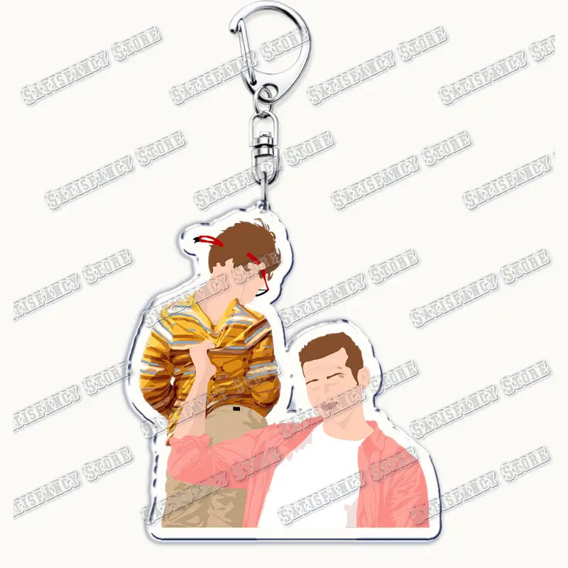 Clear acrylic keychain featuring two illustrated figures in casual pose wearing yellow striped shirt and pink jacket for 9-1-1 TV show firefighter gift.