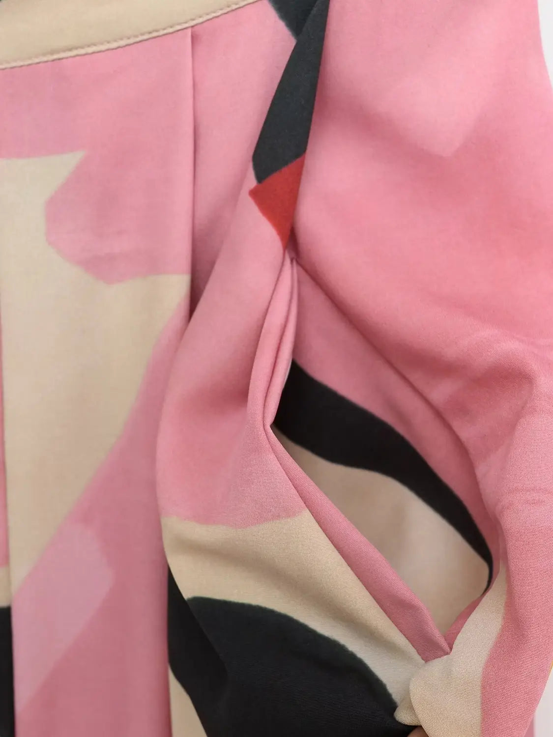 Ein weiches, abstrakt gemustertes Schal-Tuch in Rosa, Beige und Schwarz aus glattem, fließendem Stoff, passend zum geometrischen Satin-Midirock
