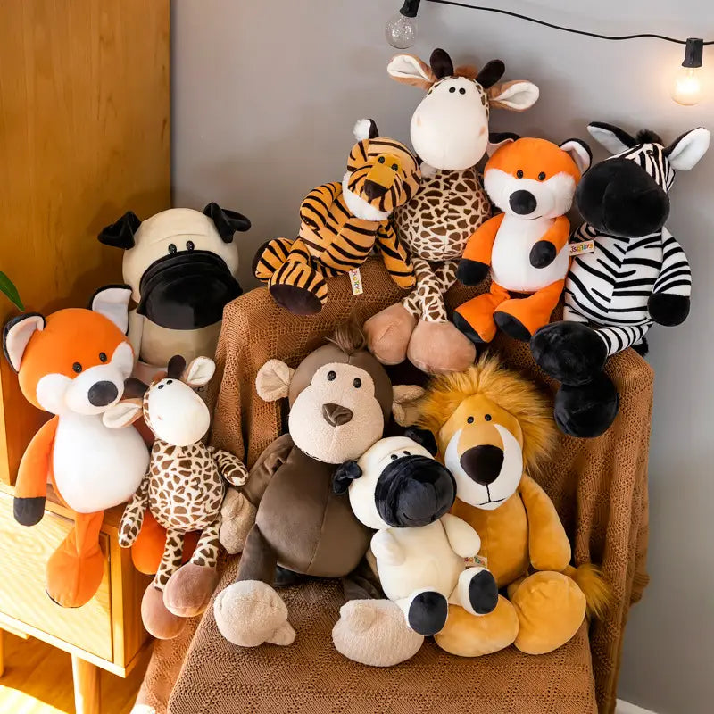 Une collection de peluches d’animaux de la jungle, composée de poupées en peluche aux motifs inspirés du safari, notamment une girafe brune et crème, un renard orange et blanc, un zèbre rayé noir et blanc, ainsi que d’autres créatures de jungle colorées telles qu’un tigre et un singe.