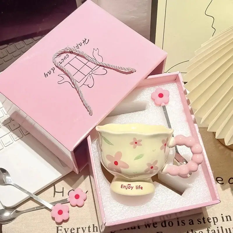 Une tasse à thé en céramique jaune pastel avec des décors floraux roses et une anse rose perlée, placée dans une boîte cadeau rose assortie pour la boîte cadeau en céramique tulipe à motif floral.