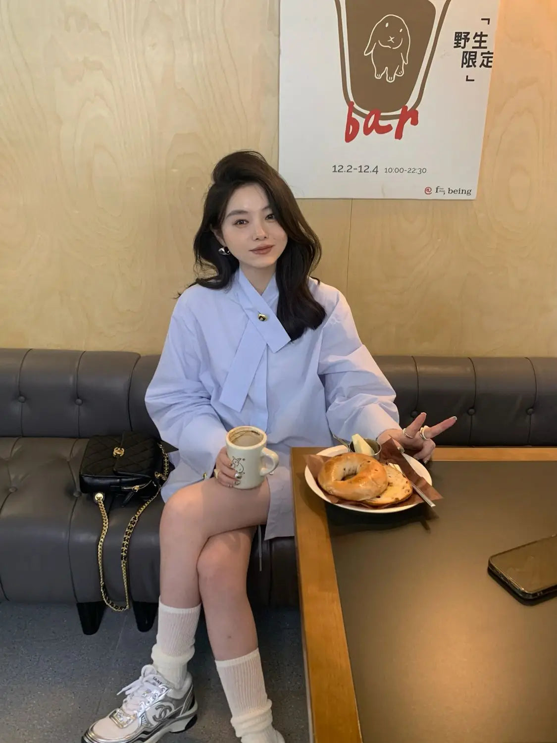 black leather crossbody bag with gold chain strap paired with light blue oversized button up shirt visible from the front