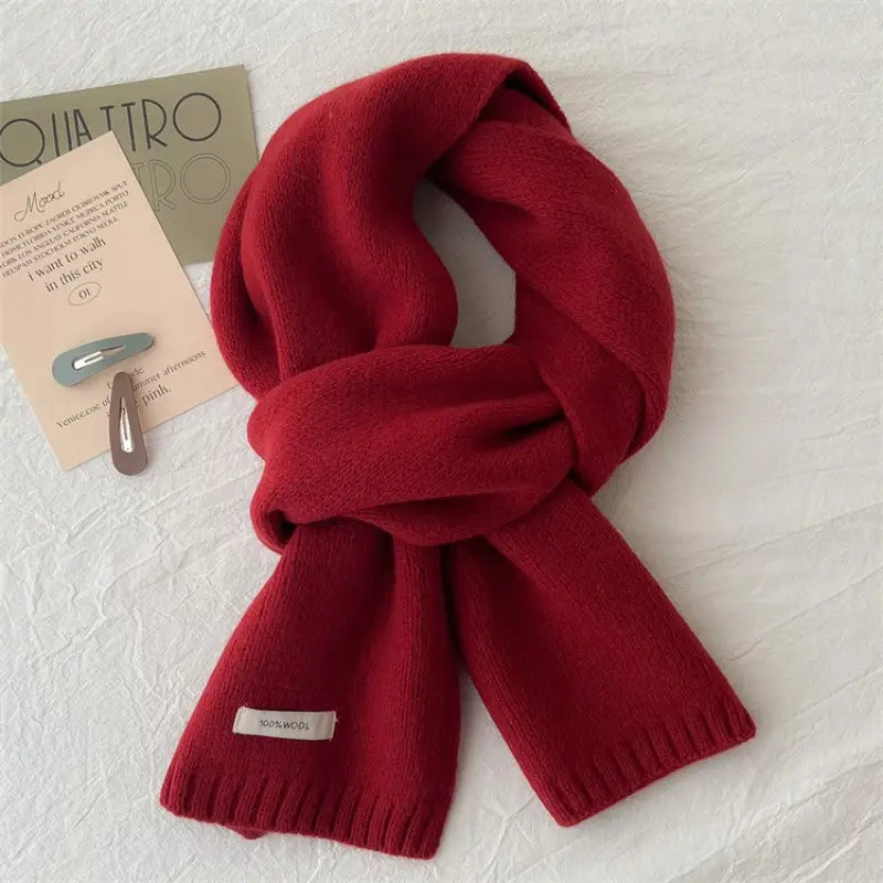 Una bufanda de invierno tejida en rojo intenso para hombres y mujeres, con textura suave y bordes acanalados.