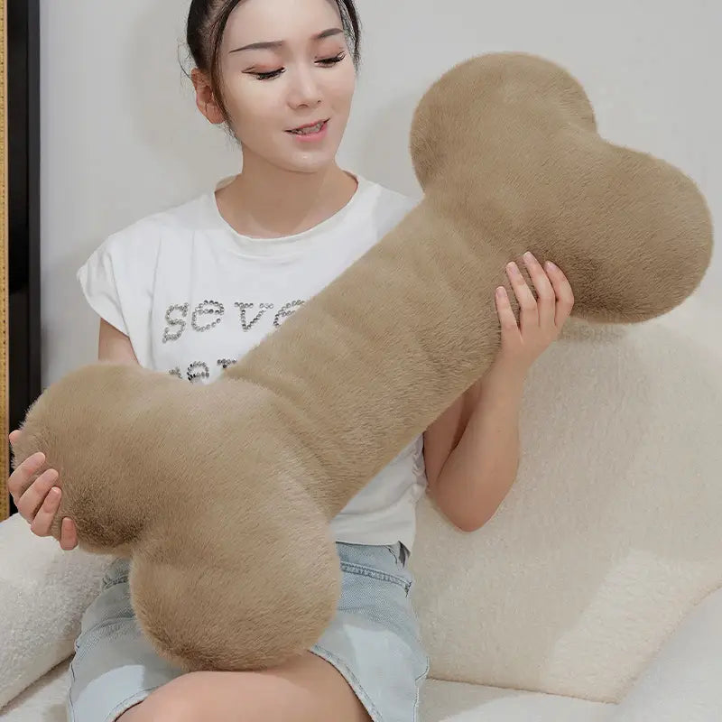 A tan-colored kawaii bone shape plush pillow made of soft fuzzy material designed as a nap cushion.