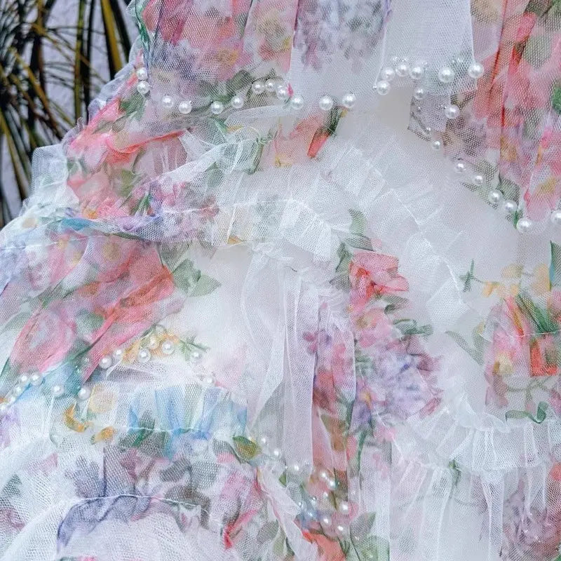 Una falda de tul floral fairycore delicada color blanco con delicadas flores en rosa suave y lavanda, y filas de pequeñas perlas a lo largo del dobladillo fruncido.