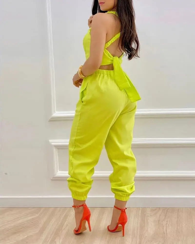Bright neon yellow halter-neck women summer printed cutout jumpsuit with back tie and elastic waistband shown from the back.